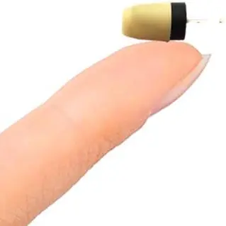 miniaturowa słuchawka leżąca na opuszku palca